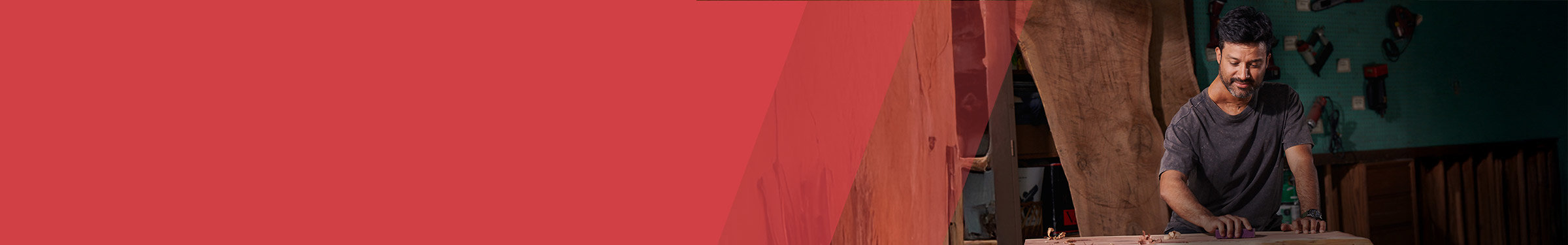 Red section header with a man to the right in a workshop that smiles while sanding a wooden surface, surrounded by tools and materials.