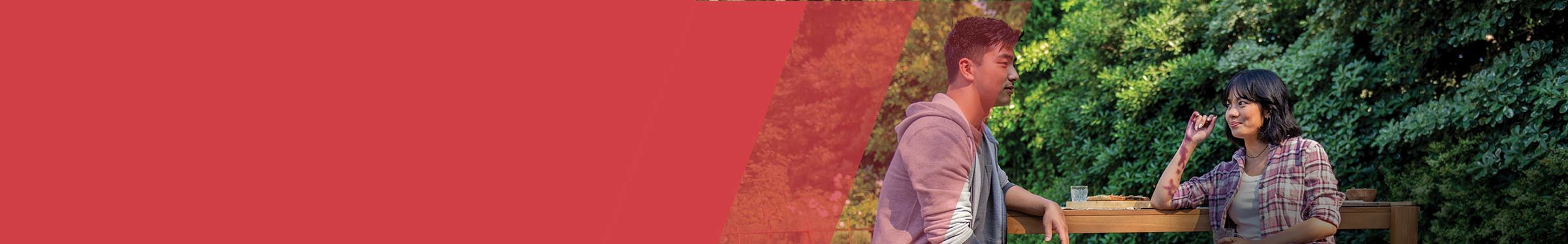Red section header with a man and woman chatting at an outdoor table, smiling and relaxed, with greenery in the background.
