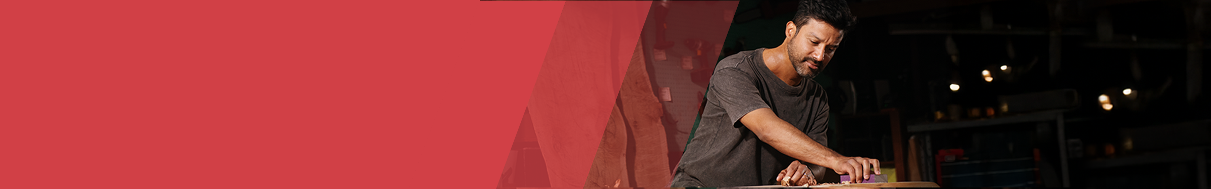 Red section header with a man to the right in a workshop sanding a surface on a table.